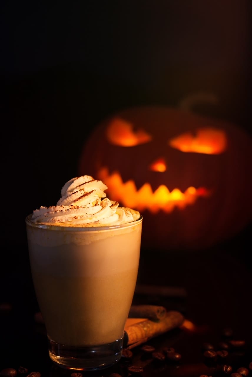 pumpkin spice latte in the foreground with a menacing jack o lantern in the back